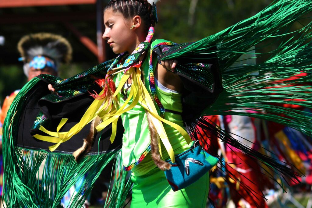 Indigenous girl in fancy shawl regalia dancing at a powwow
